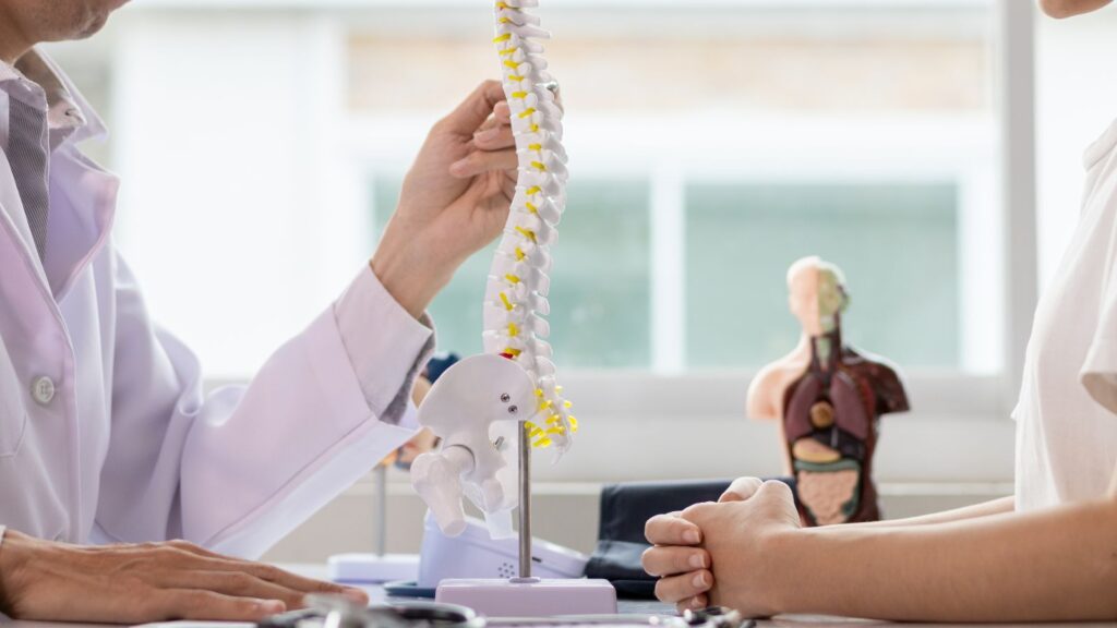 Doctor talking to a patient about Adjacent Segment Disease using a spine model.