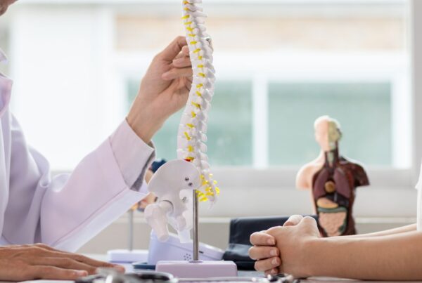 Doctor talking to a patient about Adjacent Segment Disease using a spine model.