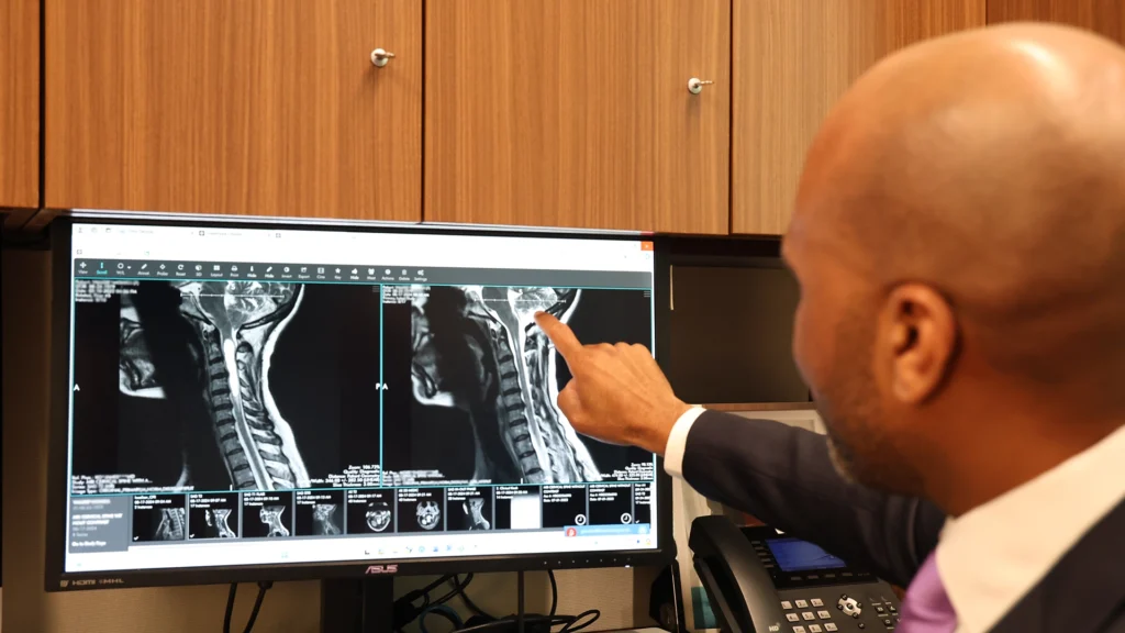 Dr. Moise Reviewing Scans of A Chiari Malformation patient, pointing at the Screen