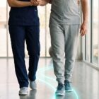 A physical therapist helps a male patient walk after a lumbar fusion.