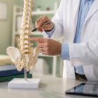 Doctor pointing to a spine model, explaining lumbar stenosis.