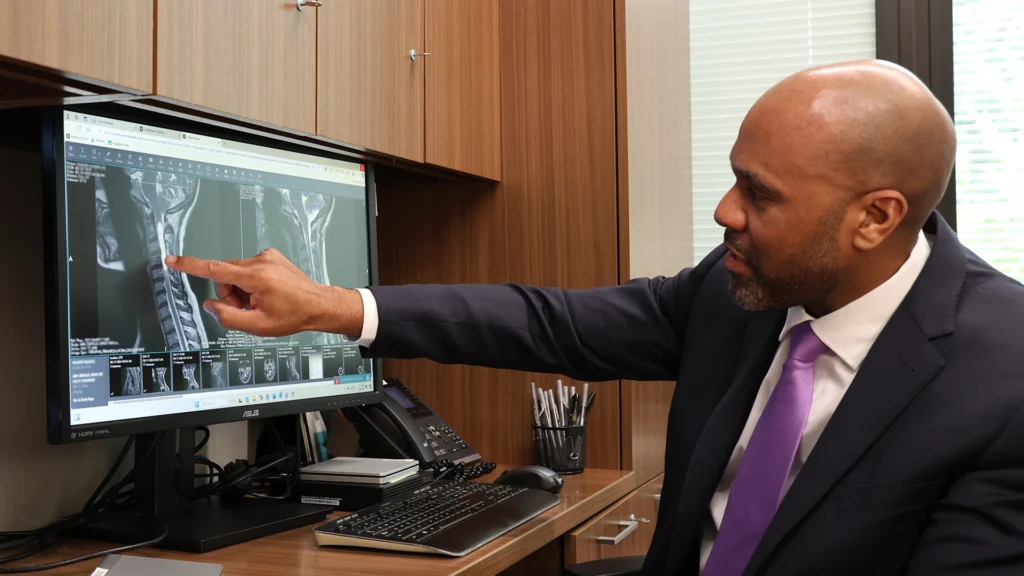 Dr. Moise Reviewing Scans of A Chiari Malformation patient, pointing at the Screen