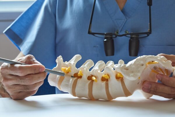 A neurosurgeon pointing at lumbar vertebra model