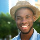 young African American man smiling with hat