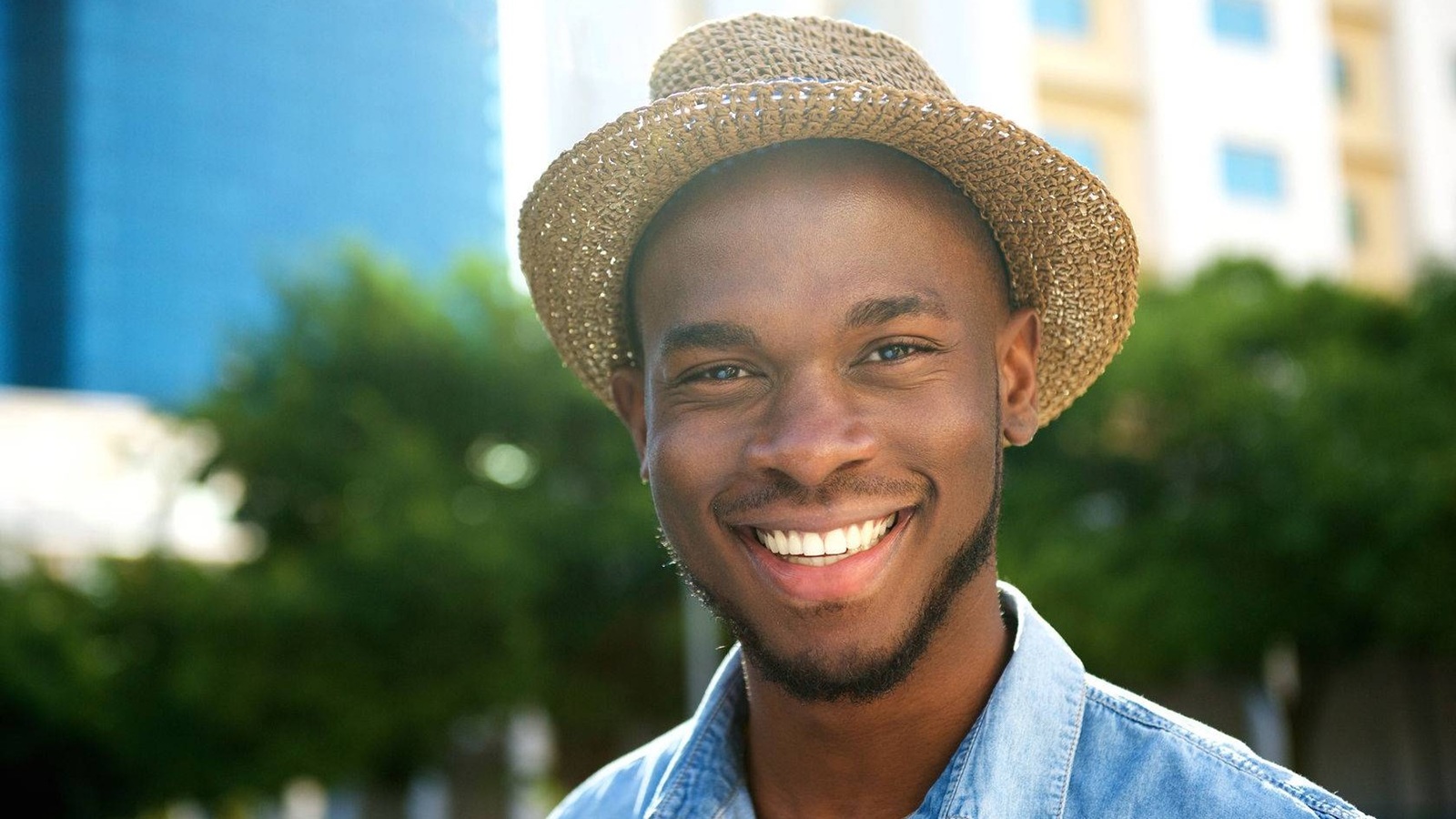 young African American man smiling with hat