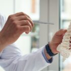 Doctor talking to a patient holding a model of a human spine.