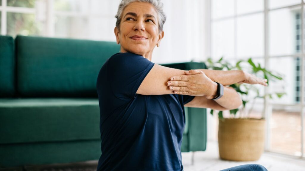 Senior woman doing a shoulder mobility exercise at home.