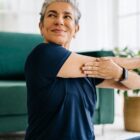 Senior woman doing a shoulder mobility exercise at home.
