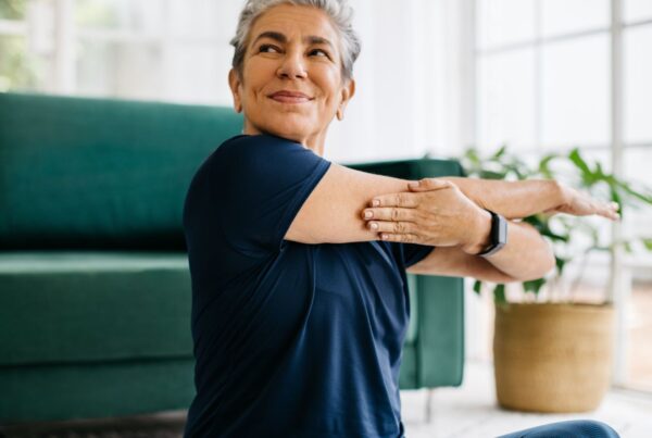 Senior woman doing a shoulder mobility exercise at home.